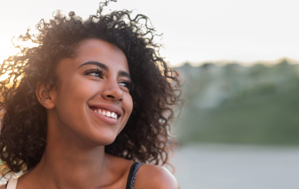 Studio shot of cute caucasian girlfriend with blond hair and braces on teeth standing in casual striped t-shirt and smiling broadly at camera, holding hands behind, enjoying great sunny day Smiling face image